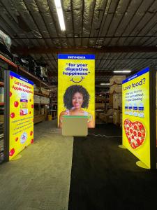 RENTAL: Modified RE-9146 Island Design with 8 ft x 16 ft Double-Sided Lightbox, Storage Closet with Locking Door, (2) 4 ft Wide x 8 ft High Double-Sided Lightboxes, RE-1576 Reception Counter, SEG Fabric Graphics, and Direct Print Sintra Graphics.