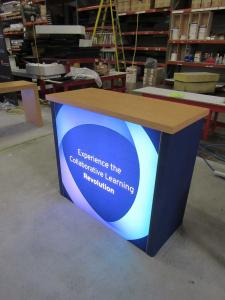 Custom Gravitee Modular Inline Exhibit with Custom Backwall Counter, Monitor Mount, Closet Storage, and Backlit GOD-1557 Reception Counter