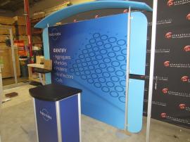 VK-1966 Backlit Inline Exhibit with Tension Fabric Graphics, Canopy, Wings, Monitor Mount, and Counter with Locking Storage
