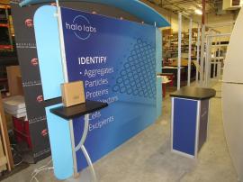 VK-1966 Backlit Inline Exhibit with Tension Fabric Graphics, Canopy, Wings, Monitor Mount, and Counter with Locking Storage