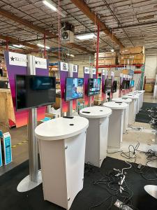 RENTAL: (9) RE-1212 Tapered Counter Kiosks with RE-1201 White Laminated Counters, Monitor Mounts, and Baseplates, Direct Print Sintra Wing Graphics, (9) Double-Sided 30" x 72" Gravitee Kiosks, Monitor Mounts, Direct Print Sintra Graphics, (27) 32" Monitor