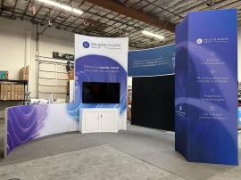 RENTAL: Modified RE-9093 Island Design with Curved Gravitee Structure, Storage Closet with Locking Door, Curved Gravitee Bridged Header, Large Curved White Laminated Counter with Locking Storage, (2) Large Monitor Mounts, 75" Monitor with HDMI Cable, 43"